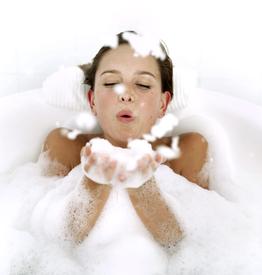 Young Woman in a Bathtub Blowing Foam from Her Hands