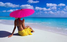 Rear view of a woman sitting with a parasol on the beach